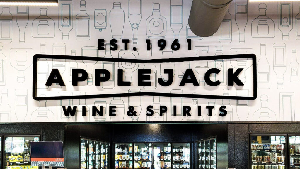 Interior feature wall with dimensional 'APPLEJACK Wine & Spirits' logo over a subtle bottle-pattern graphic.