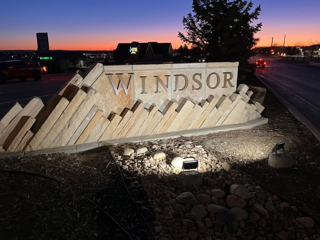 Stone monument entry sign for the Town of Windsor illuminated at dusk.

local